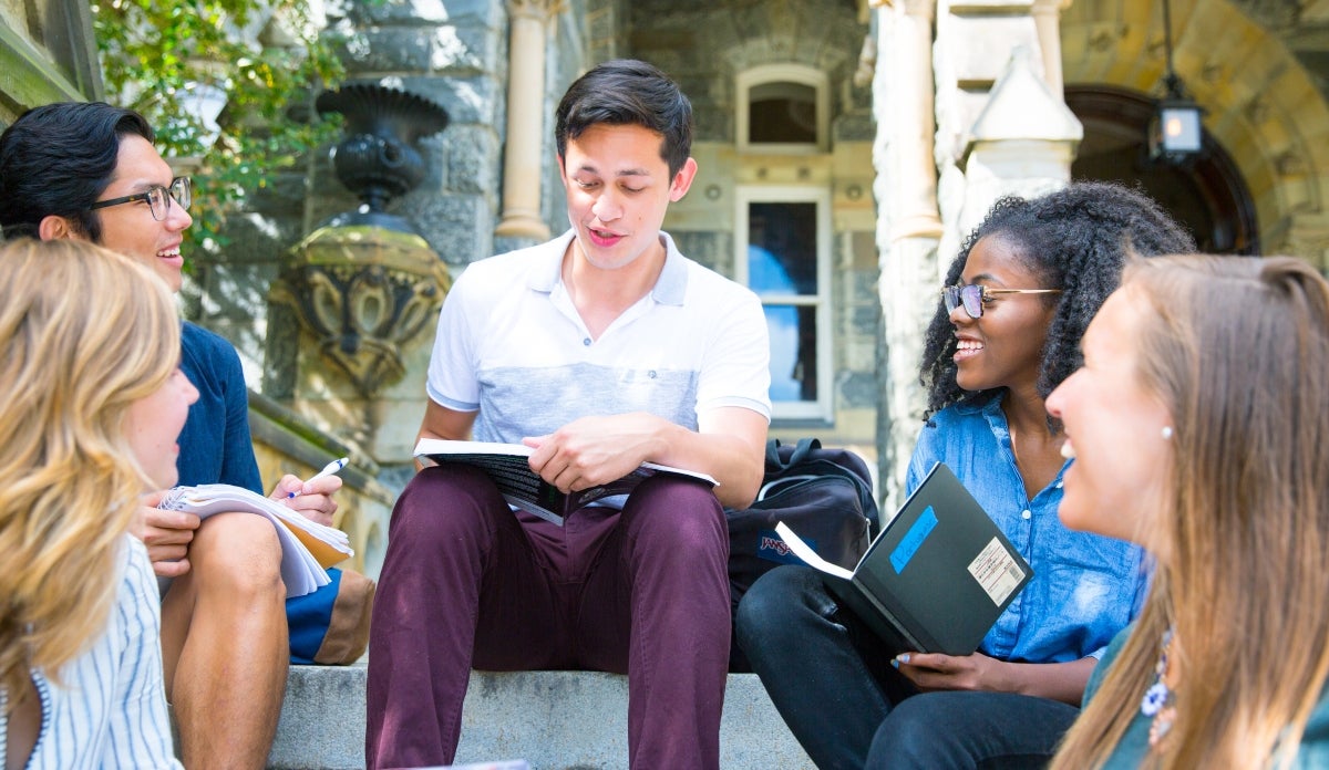 Five students studying together on the steps of Healy Hall