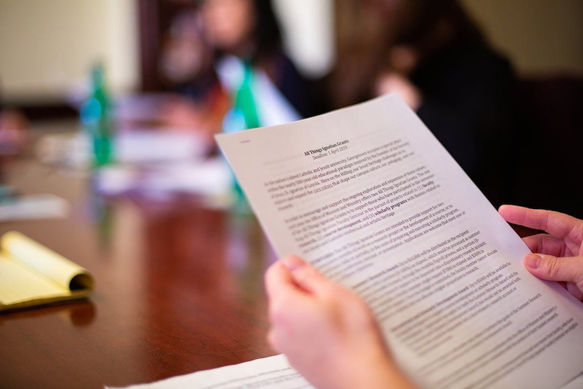 Faculty member holding a document during a seminar.